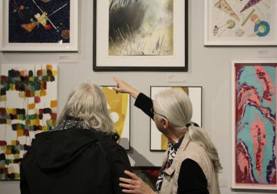 People look at painting at the people's art show.