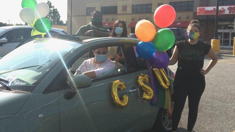 A CSU student standing by one of the cars in the CLE Pride Ride.