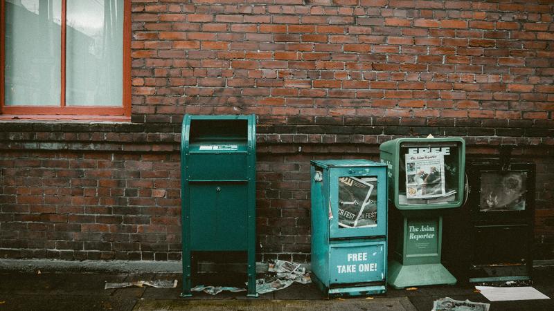 Run down news stands line a sidewalk.