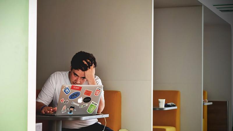 Student looking distressed while looking at a laptop 