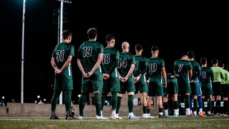 CSU soccer players stand for the national anthem.