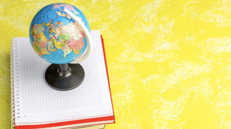A globe sitting on top of a stack of notebooks.