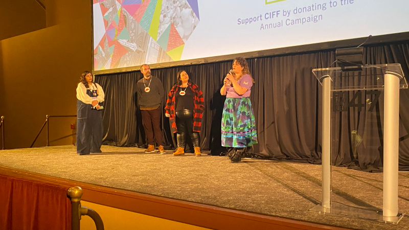 A member of the Cleveland International Film Festival stands on stage with three filmmakers.