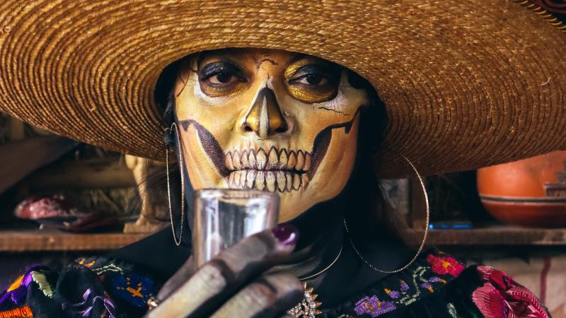 A woman dons makeup resembling La Calavera Catrina.