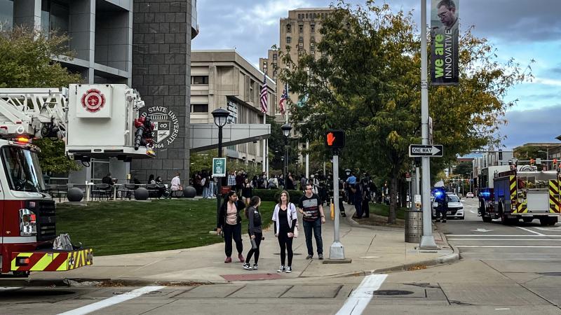 Students walking outside of campus amidst firetrucks.