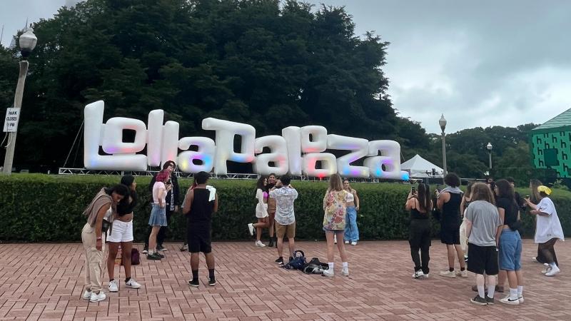People wait by Lollapalooza sign to take pictures upon entering the festival.