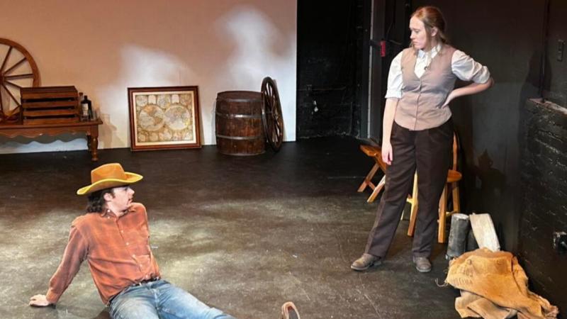 Randall McCain (left, played by Nicholas Hassan) and Cecilia Donne (right, played by Katie Steim) sitting under the Louisiana sun and waiting for their train to arrive. 