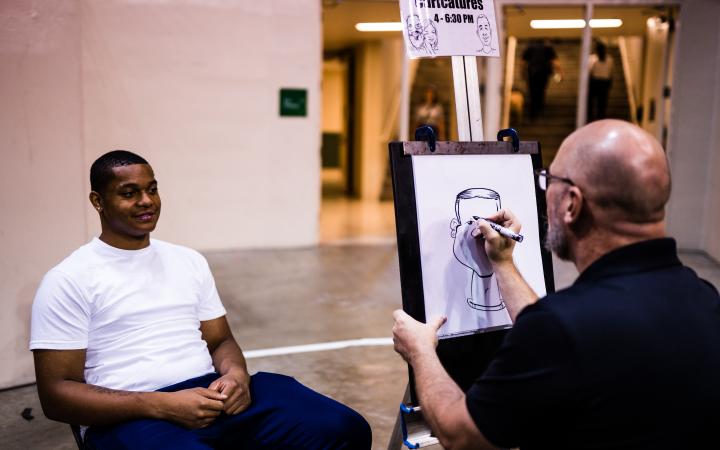 Student getting drawn by a caricature artist