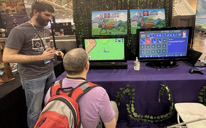  Dan Jewett, creator of Violets of Amicus, left, explains the mechanics of his game to a participant. (credit: Alex Martinez)  