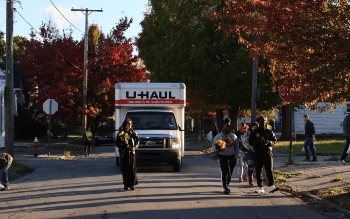 BoricuaLibra Collective member Isabela Robert, left, New Era Cleveland community leader chairman Fahiem,middle, and NES President Rameer Askew, front right, handing out flowers during a community engagement walk on Oct. 26, 2025. (credit: Milo Pond.)
