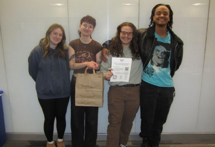 From left, Secretary Olivia Stein, President Audrey Menner, Vice President Henry Clay and Treasurer Jude Ouma stand together during the first meeting of Students for a Just Society on Feb. 26, 2026, in Berkman Hall, Room 319 at Cleveland State University. (Credit: Morgan Alten)