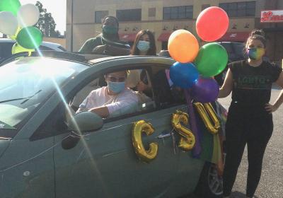 A CSU student standing by one of the cars in the CLE Pride Ride.