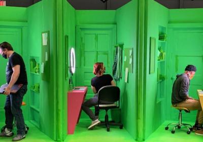 three actors on green screen set divided into cubicles