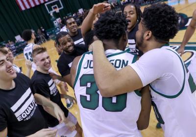 Cleveland State basketball players embrace on court after win against Robert Morris