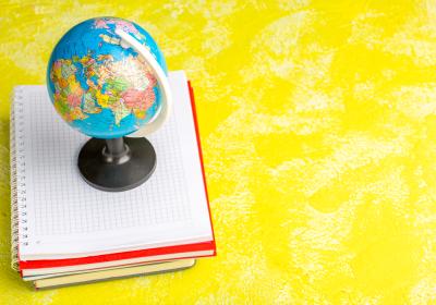 A globe sitting on top of a stack of notebooks.