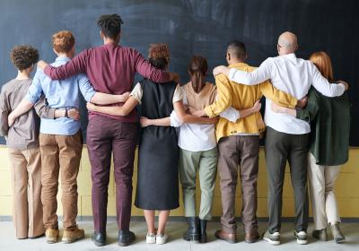 A group of diverse people standing with their backs to the camera.