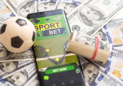 U.S. dollars, a mobile phone with a betting app and a soccer ball