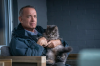 Tom Hanks as Otto Anderson sitting on his porch, holding his pet cat in a still from Sony's "A Man Called Otto"